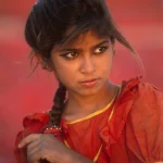 Jeune fille en robe rouge regardant au loin