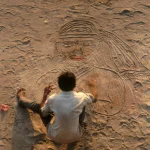 Dessin sur sable par un homme sur une plage