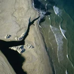 Vue aérienne d'une plage avec marées et traces de véhicule