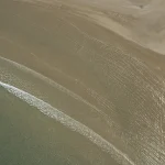 Vue aérienne d'une plage déserte avec vague déferlante