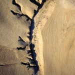 Vue aérienne des formes géologiques arides et des champs labourés