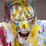 Visage coloré criant d'adulte recouvert de peinture