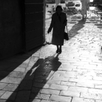 Femme âgée marchant dans une ruelle pavée en lumière du jour