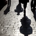 Ombres de passants sur un chemin pavé