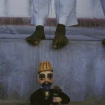 Marionnette traditionnelle devant un marionnettiste en pantalon blanc