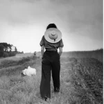 Femme avec chapeau marchant dans un champ