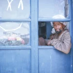Homme à la porte bleue d'une boutique