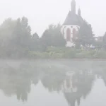 Église dans le brouillard au bord d'un lac