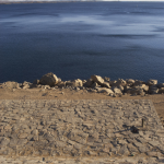 Vue sur un lac avec une étendue rocheuse au premier plan