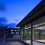 Vue Nocturne d'un Bâtiment Moderne avec Reflets de Lumières Urbaines