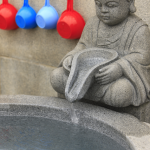 Statue de moine bouddhiste avec louches colorées