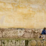 Enfant courant devant un mur en pierre vieillie