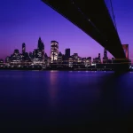 Vue nocturne d'une ville moderne et son pont emblématique.