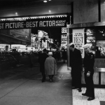 Scène Nocturne à Times Square avec Passants et Affiches de Films