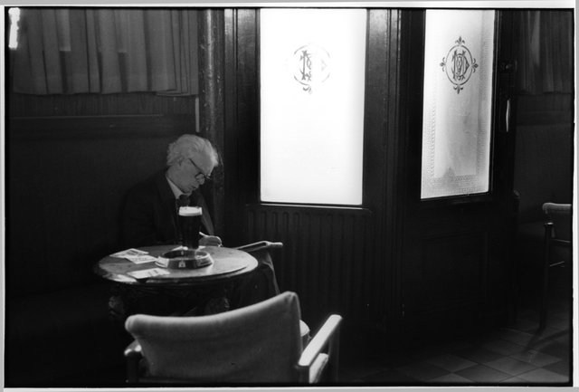 AKG1724172.webp Homme âgé assis dans un café en train de lire – Image 1