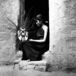 Femme tissant une couronne traditionnelle devant une porte en adobe