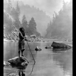 Pêcheur solitaire sur une rivière montagneuse embrumée