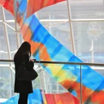 Femme regardant téléphone sous installations colorées