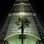 Gratte-ciel illuminé avec palmier au premier plan de nuit