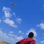 Homme regardant un avion sous un ciel bleu