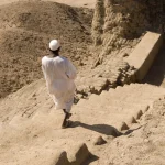 Homme en tenue traditionnelle descendant des marches dans un désert