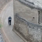 Vieil homme marchant dans une ruelle étroite le long d'un bâtiment ancien
