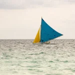 Voilier avec Voiles Bleues et Jaunes sur l'Océan