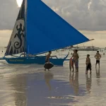 Voilier bleu sur la plage au coucher du soleil