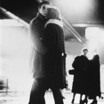 Couple enlacé sous un pont illuminé la nuit