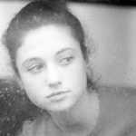 Jeune femme pensant à travers une vitre brumeuse