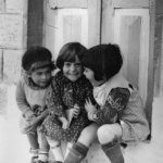 Enfants souriants assis devant une porte