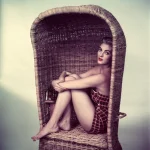Femme assise dans un fauteuil en osier