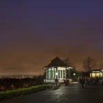 Vue nocturne d'un kiosque avec public dans un parc urbain