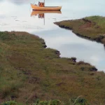 Bateau de pêche tranquille sur une rivière bordée de montagnes