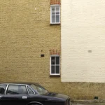 Voiture garée devant un mur en briques avec fenêtres