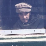 Homme regardant par la fenêtre d'un bus avec inscription "LADIES"