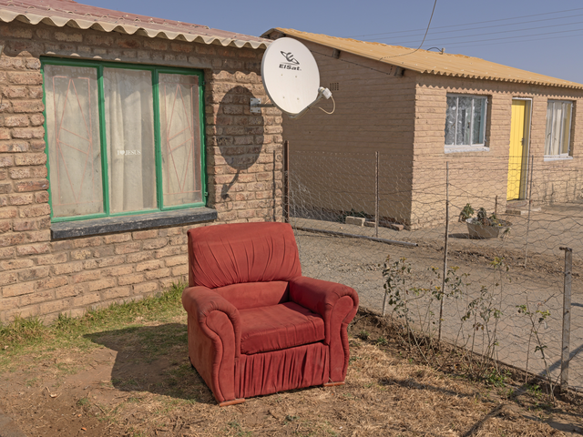 AKG2144626.webp Fauteuil rouge devant la maison en brique – Image 1