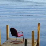 Chaise rouge solitaire sur un ponton au bord de l'eau