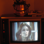 Téléviseur rétro avec une actrice à l'écran et un vase de fleurs