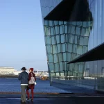 Deux personnes devant un bâtiment moderne en bord de mer