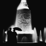 Silhouettes devant une fontaine illuminée de nuit