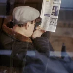 Homme lisant un journal avec loupe