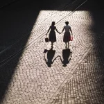 Deux Femmes Marchant Main dans la Main sur une Rue Pavée
