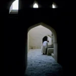 Homme en habit traditionnel dans un couloir d'une architecture ancienne