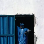 Homme en tenue traditionnelle devant une porte bleue