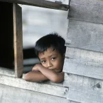 Enfant regardant par la fenêtre d'une maison en bois