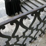 Groupe de personnes en manteaux noirs sur un escalier extérieur en pierre