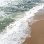 Surfeur sur la plage désertée au bord de l'océan