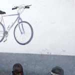 Deux hommes discutant près d'un mur avec une peinture de vélo