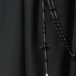 Croix en or et chapelet noir sur fond sombre